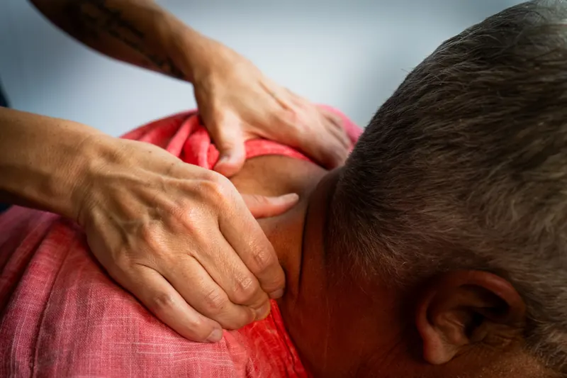 Hände der Masseurin lösen Verspannungen im Nacken
