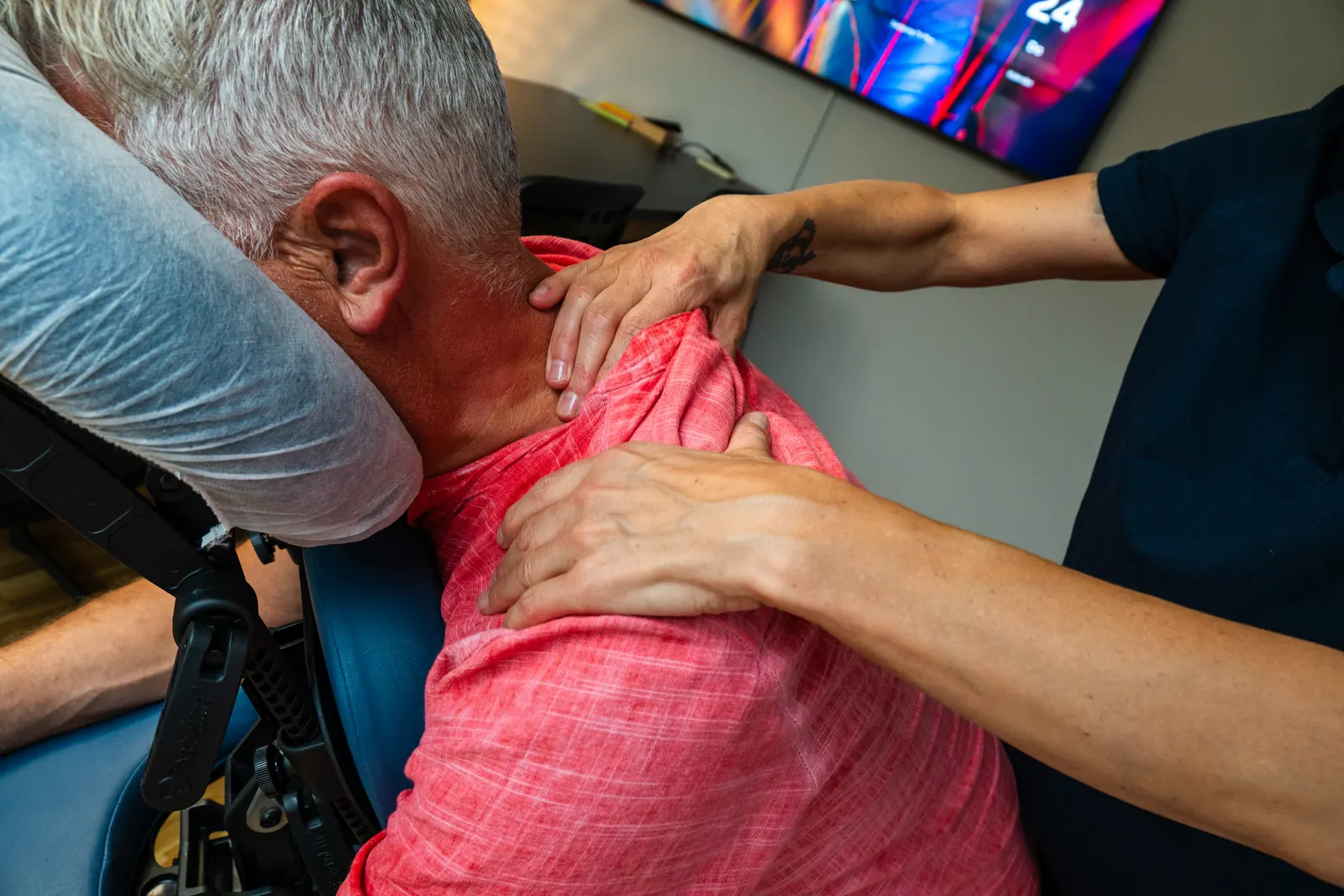 Masseurin von Workpilot massiert einen Mitarbeiter auf dem Massagestuhl im Sitzungszimmer