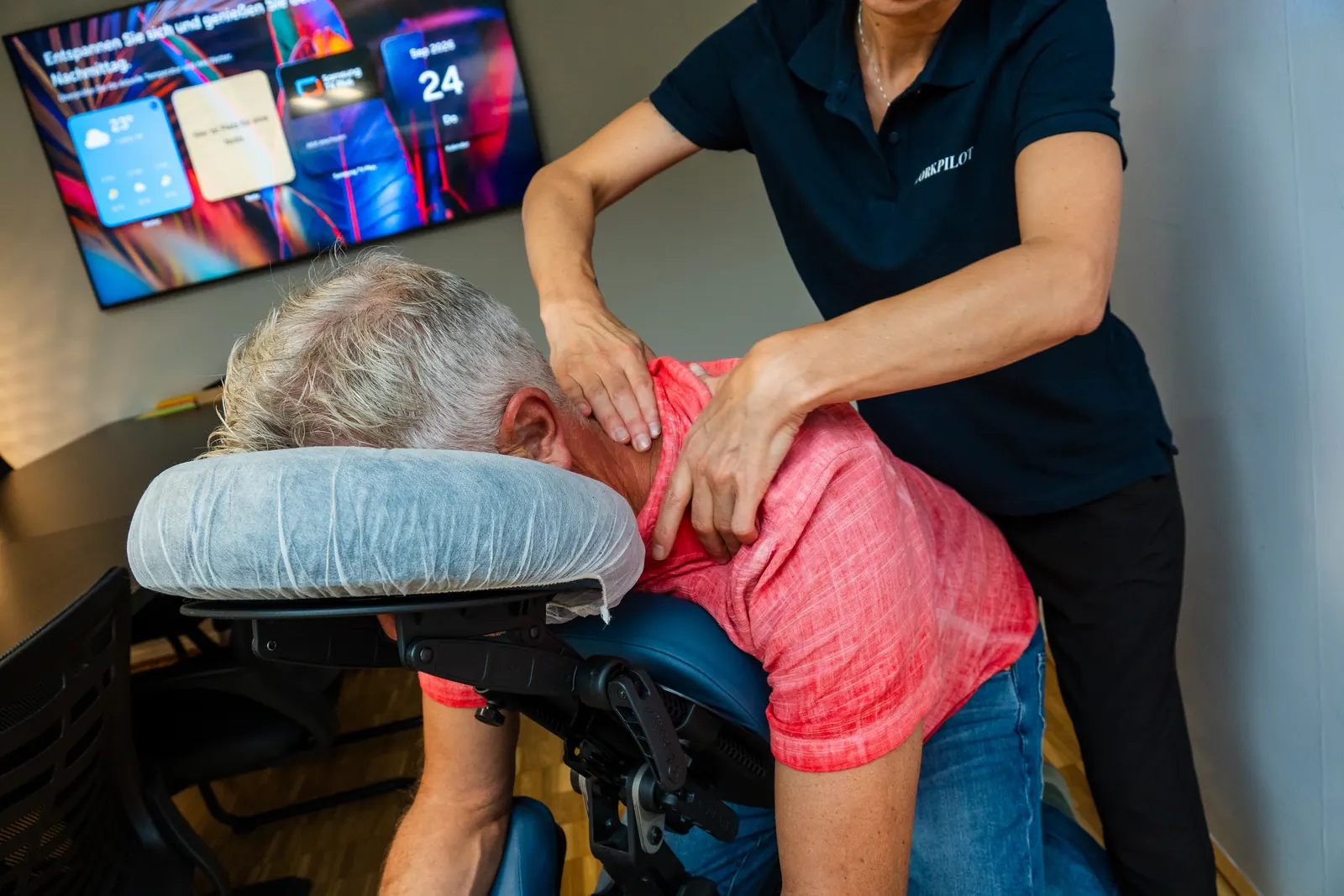 Masseurin von Workpilot massiert einen Mitarbeiter auf dem Massagestuhl im Büro
